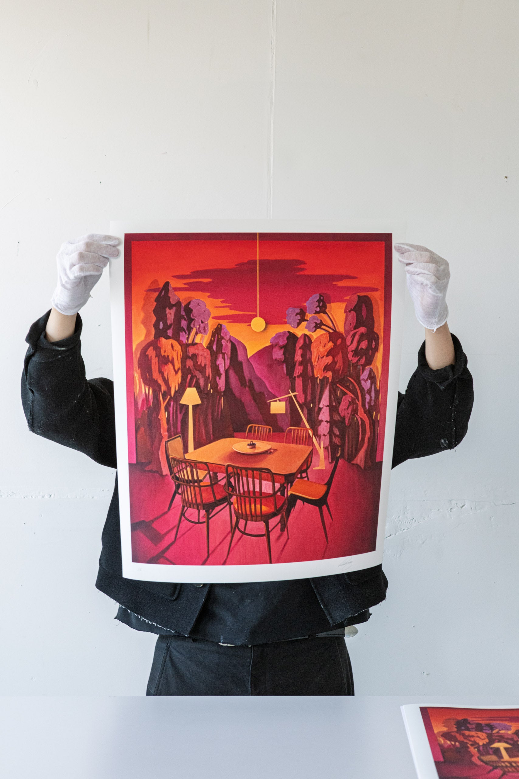 Artist holding Print artwork of a stylized dining room with red and orange tones.